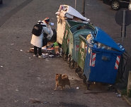 Rifiuti donna rovista fra i cassonetti
